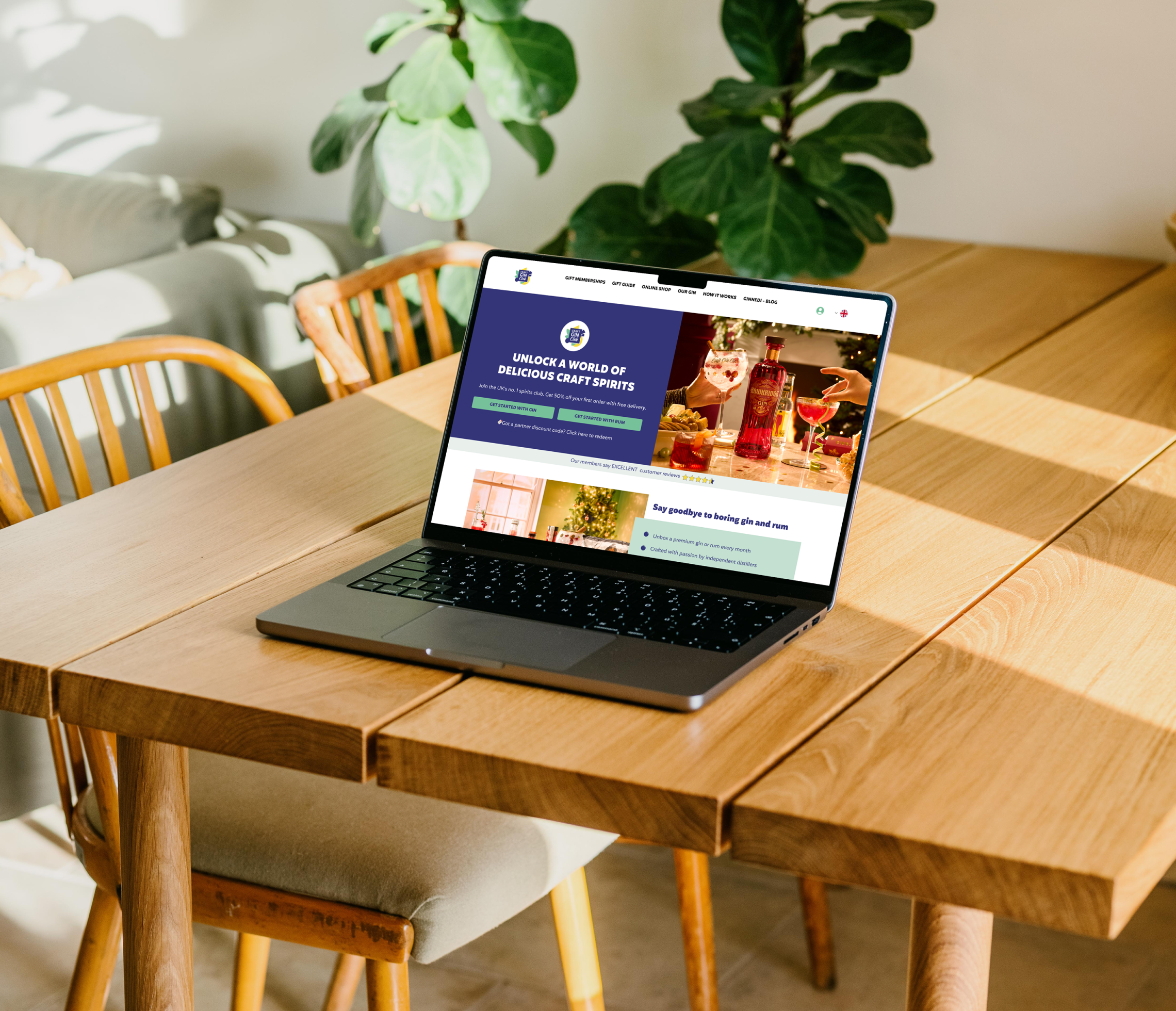A laptop displaying a website sits open on a wooden dining table with sunlight streaming in. Wooden chairs and leafy green plants are in the background, creating a cozy, inviting atmosphere—perfect for exploring doggy day care software solutions.
