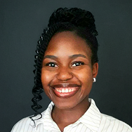 A woman with dark braided hair, wearing a white collared shirt and earrings, smiles against a plain dark background.