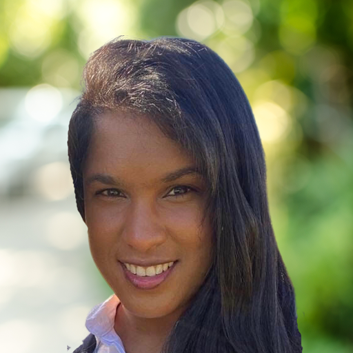 A woman with long dark hair smiles at the camera, standing outdoors with sunlight and greenery softly blurred in the background, embodying the fresh perspective and innovation of Bitcube.